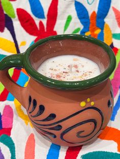 a clay pot filled with white liquid on top of a colorful blanket