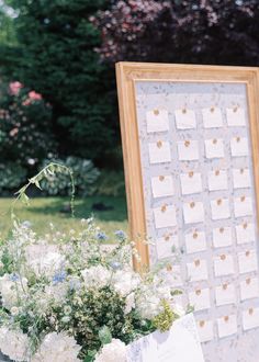 a bouquet of flowers sitting on top of a table next to an easel with pictures