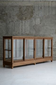 a wooden cabinet with glass doors in front of a concrete wall