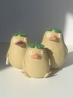 three ceramic birds with green leaves on their heads