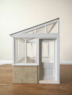 a doll house made out of bricks on top of a wooden floor next to a white wall