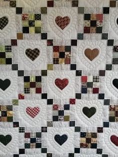 a quilted wall hanging with many different hearts on it's sides and squares