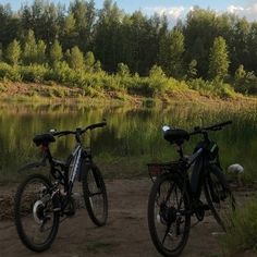 two bikes parked next to each other in front of a body of water and trees