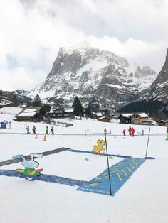 people playing in the snow with mountains in the background