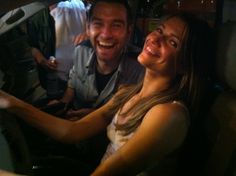 a man and woman sitting in the passenger seat of a car smiling at the camera