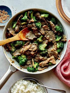 a pan filled with beef and broccoli next to rice on a table top