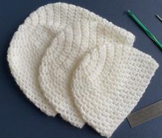 a crocheted white hat next to two knitting needles and a pair of scissors