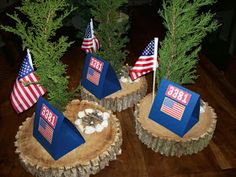 three small trees with flags on them are sitting in the middle of a log table