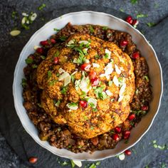 some food in a white bowl on a black table with red and green toppings