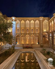 an ornate building lit up at night with its reflection in the water