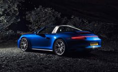 a blue sports car parked in front of a rocky area at night with its lights on