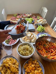 a wooden table topped with lots of plates and bowls filled with different types of food