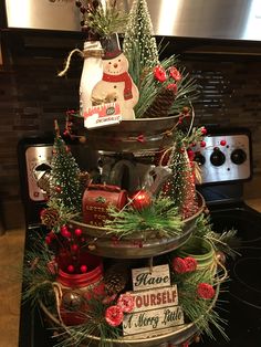 a three tiered christmas tree on top of a stove with ornaments and decorations around it