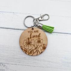 a wooden keychain with flowers engraved on it and the words you are loved