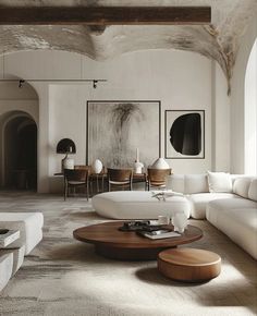 a living room filled with white furniture and art on the wall above it's coffee table