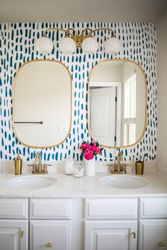 two sinks in a bathroom with blue and white wallpaper