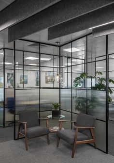 two chairs and a table in an office setting with glass partitions to the wall