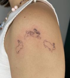 a woman's arm with two rabbits on it and one bunny running behind her