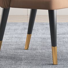 an upholstered chair with two gold legs and a beige seat cushion on a carpeted area