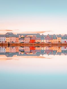 some buildings are reflected in the water and one is on the other side of the lake