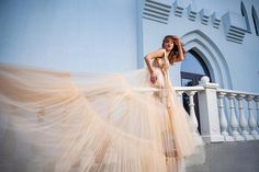 a woman in a long dress is standing on a balcony with her hair blowing in the wind