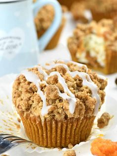 a muffin with white icing sitting on top of a plate next to a fork