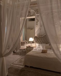 a white bed sitting under a canopy in a bedroom