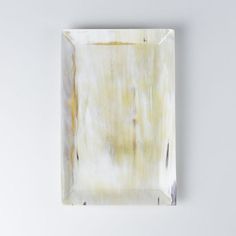 a square plate with yellow and white paint on it