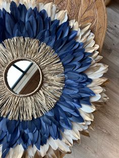 a mirror that is sitting on top of a table with blue and white feathers around it