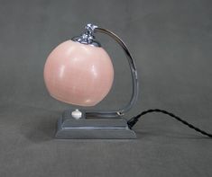 a pink lamp sitting on top of a table next to a black corded phone