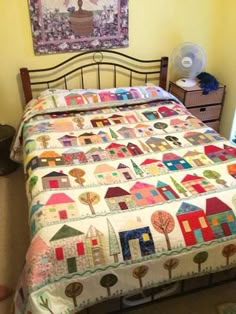 a bed with a quilt on top of it in a bedroom next to a fan