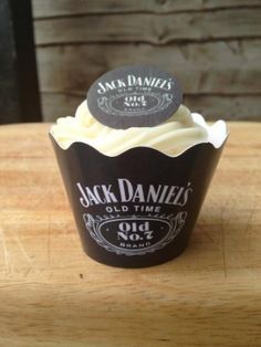 a cupcake sitting on top of a wooden table next to a bottle of jack daniels