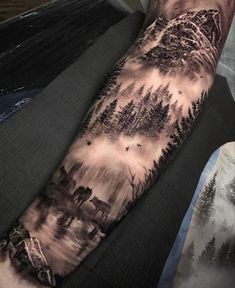 a man's arm with trees and mountains on it