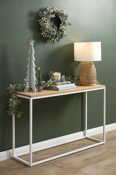 a white table with a christmas tree on it and a wreath hanging from the wall