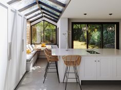 an open kitchen and living room area with white cabinets, counter tops, and bar stools