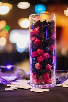 a vase filled with pink and purple flowers on top of a black cloth covered table