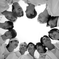 a group of young people standing in a circle looking up at the camera with smiles on their faces