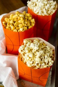 three orange bags filled with popcorn sitting on top of a table