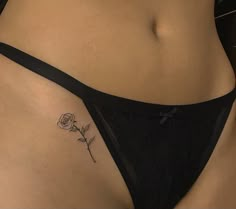 a woman's stomach with a rose tattoo on her left side ribcage