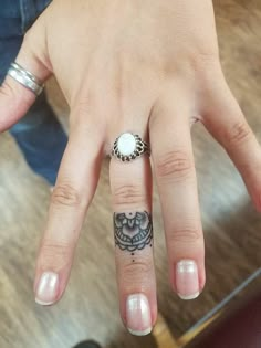 a woman's hand with a ring on it and an owl tattoo on the middle finger