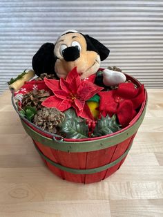 a stuffed dog sitting in a red basket filled with christmas decorations and poinsettis