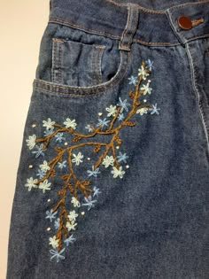 a pair of jeans with embroidered flowers on them