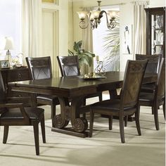 a dining room table with chairs and a china cabinet in front of the window,