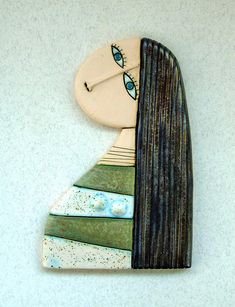 a ceramic clock with a woman's face and long hair, on a white wall