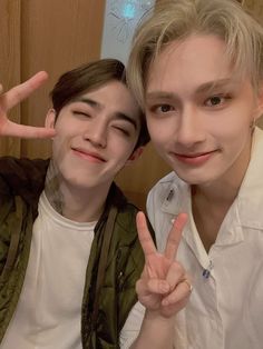 two young men posing for the camera with their fingers in the shape of peace signs