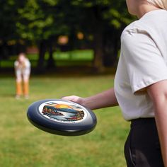 a woman holding a frisbee on top of a lush green field next to another person