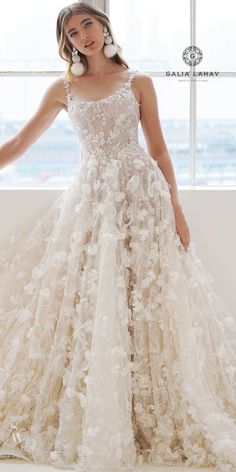 a woman in a wedding dress with flowers on the skirt is posing by a window