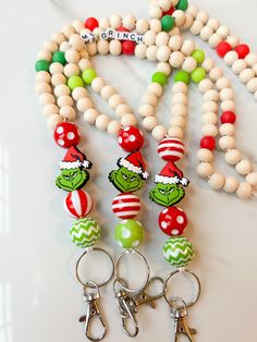 the grinch beads are on display next to two keychains that have been made out of wood beads