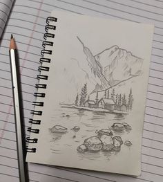 a notebook with a drawing of a house on the water and mountains in the background