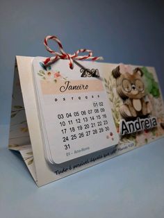 a calendar with a teddy bear on it and a ribbon tied around the front end